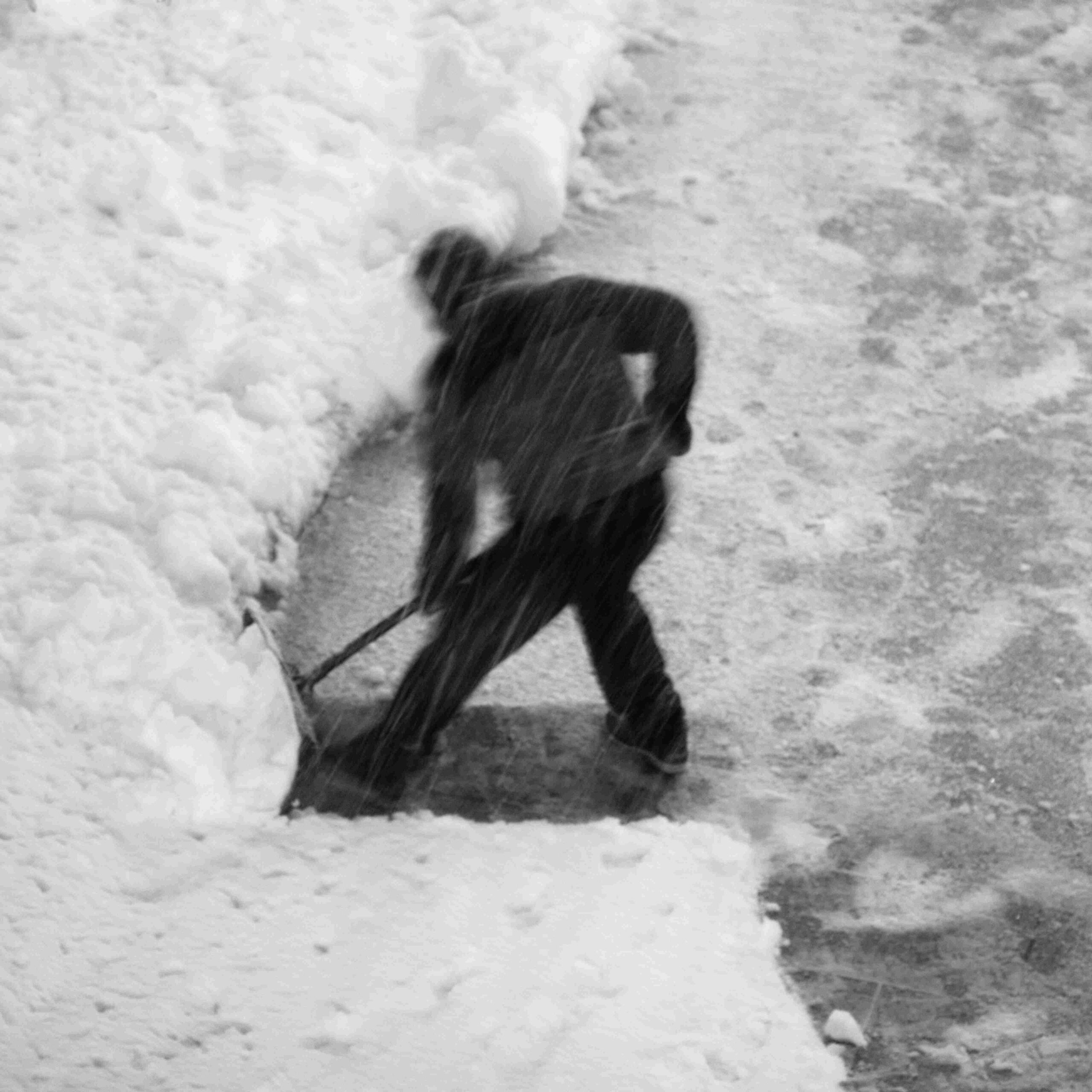 A lone man shoveling snow on a broad, textured expanse, his figure blurred by motion—a study in perseverance and existential labor.
